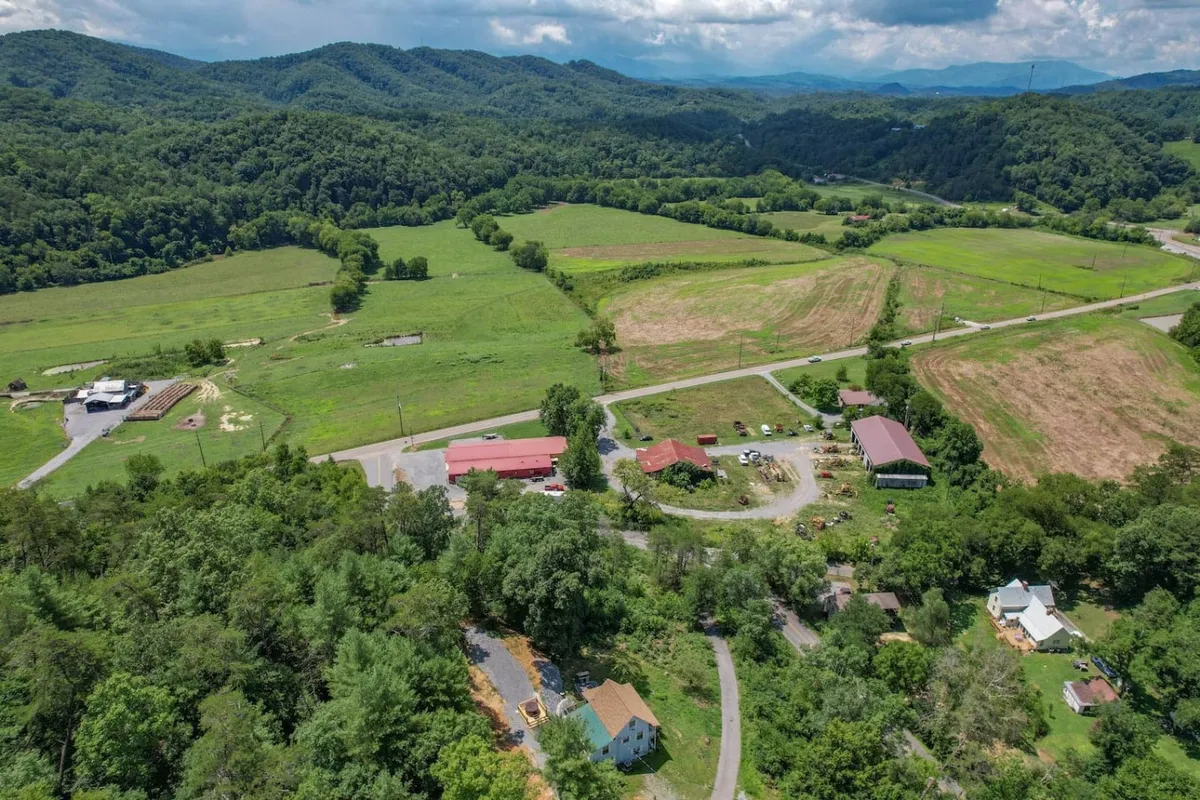 A broad view of rolling hills, scattered buildings, dirt roads, and lush greenery. The landscape hints at the wider Sevierville area, providing a sense of local context with opportunities for hiking, community gatherings, and seasonal festivities.
