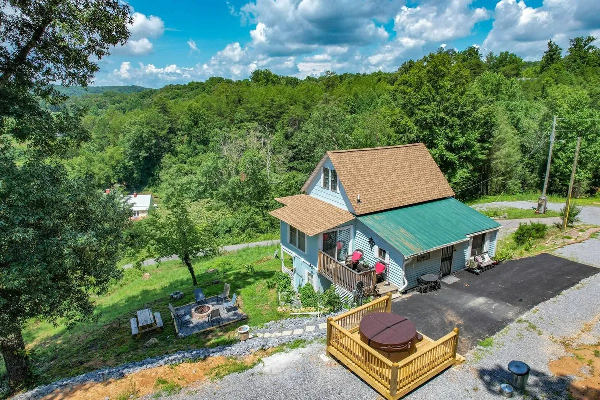 This image captures the exterior of the house, featuring a hot tub and fire pit surrounded by trees. The deck area offers views of the wooded surroundings and is an inviting spot for relaxation and outdoor gatherings.